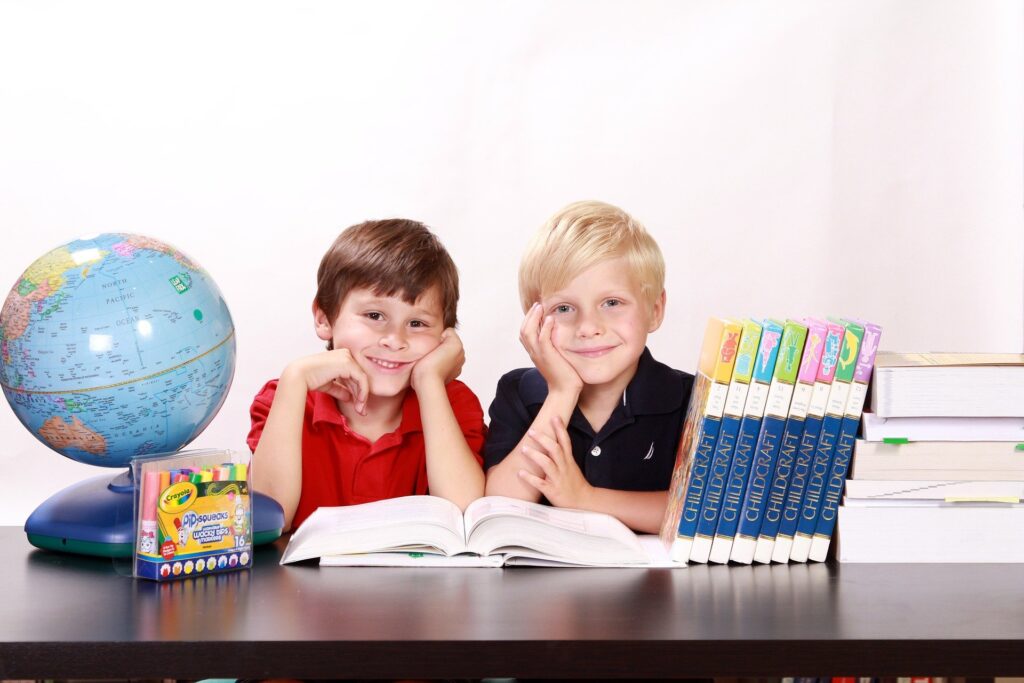 地球儀と本に囲まれて幸せそうに勉強する男子二人
