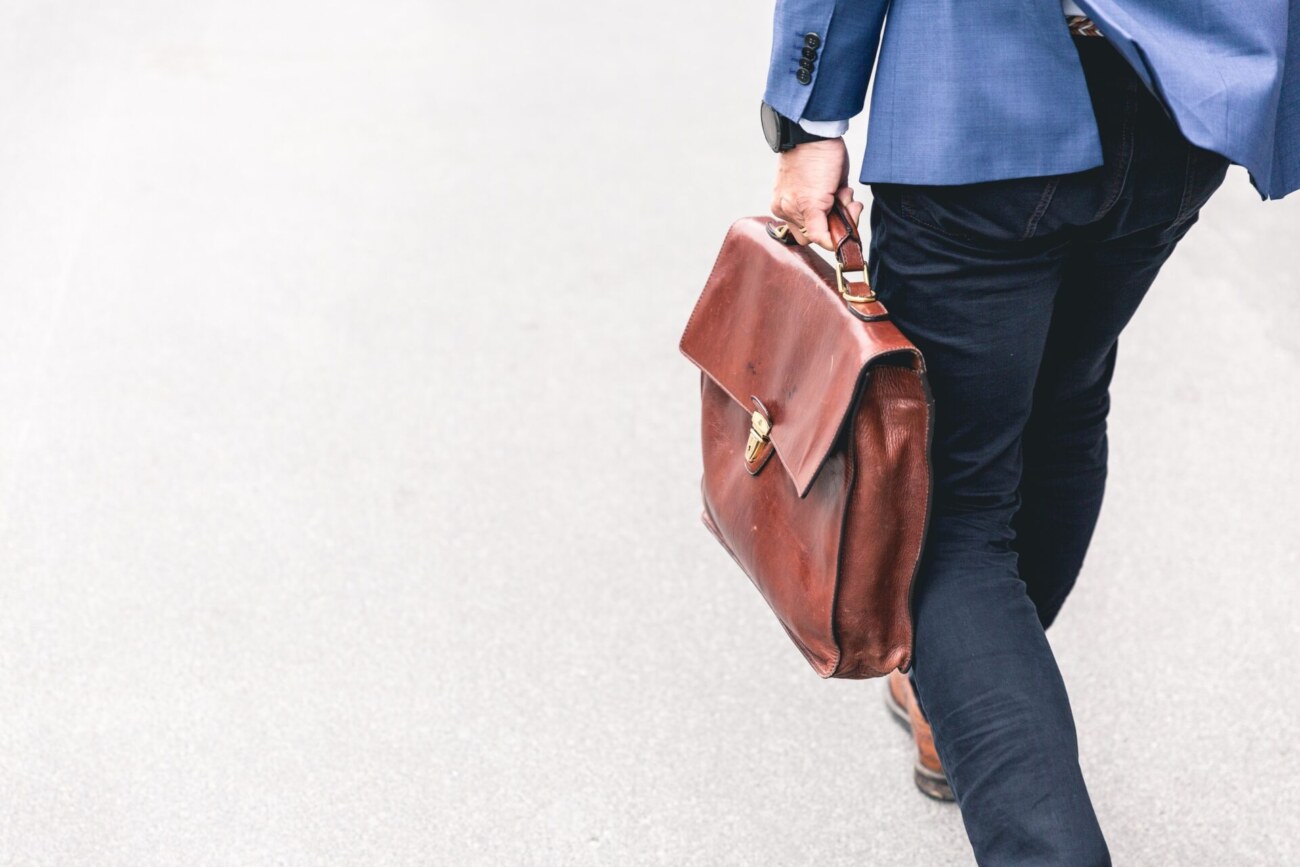 茶色の仕事用鞄を持って歩いている男性の写真