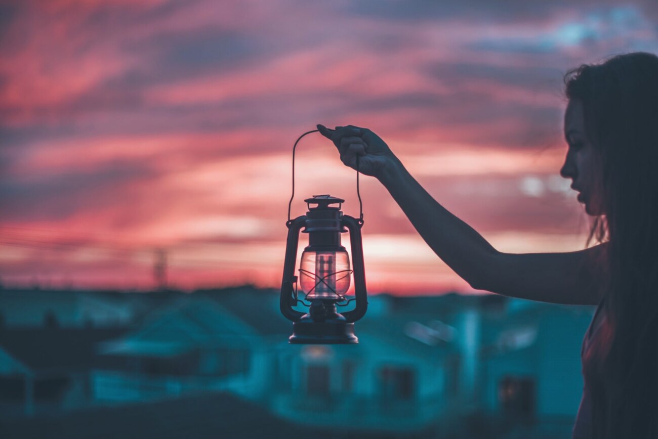 夕暮れを背景にランプを掲げる人の写真